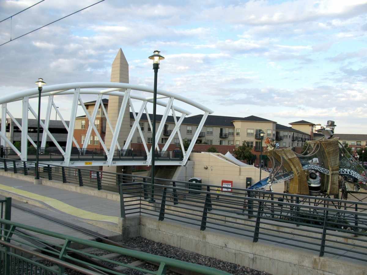 Pedestrian bridge over street with city center in background for article Englewood Colorado for newcomers moving to the Denver area.