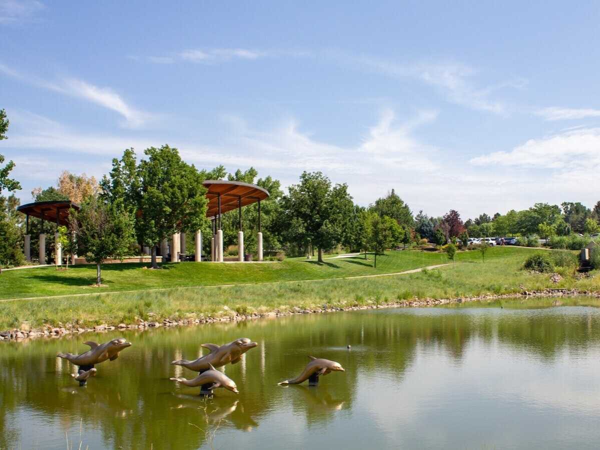 Westlands Park with dolphin sculptures over pond for article Greenwood Village Colorado for newcomers moving to Denver area.