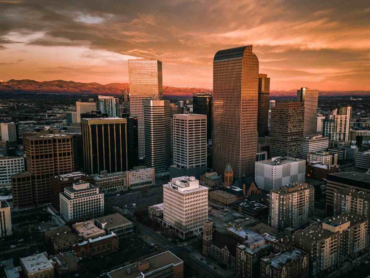 Downtown city of Denver with orange sky for article Denver Colorado for newcomers moving to Denver area.