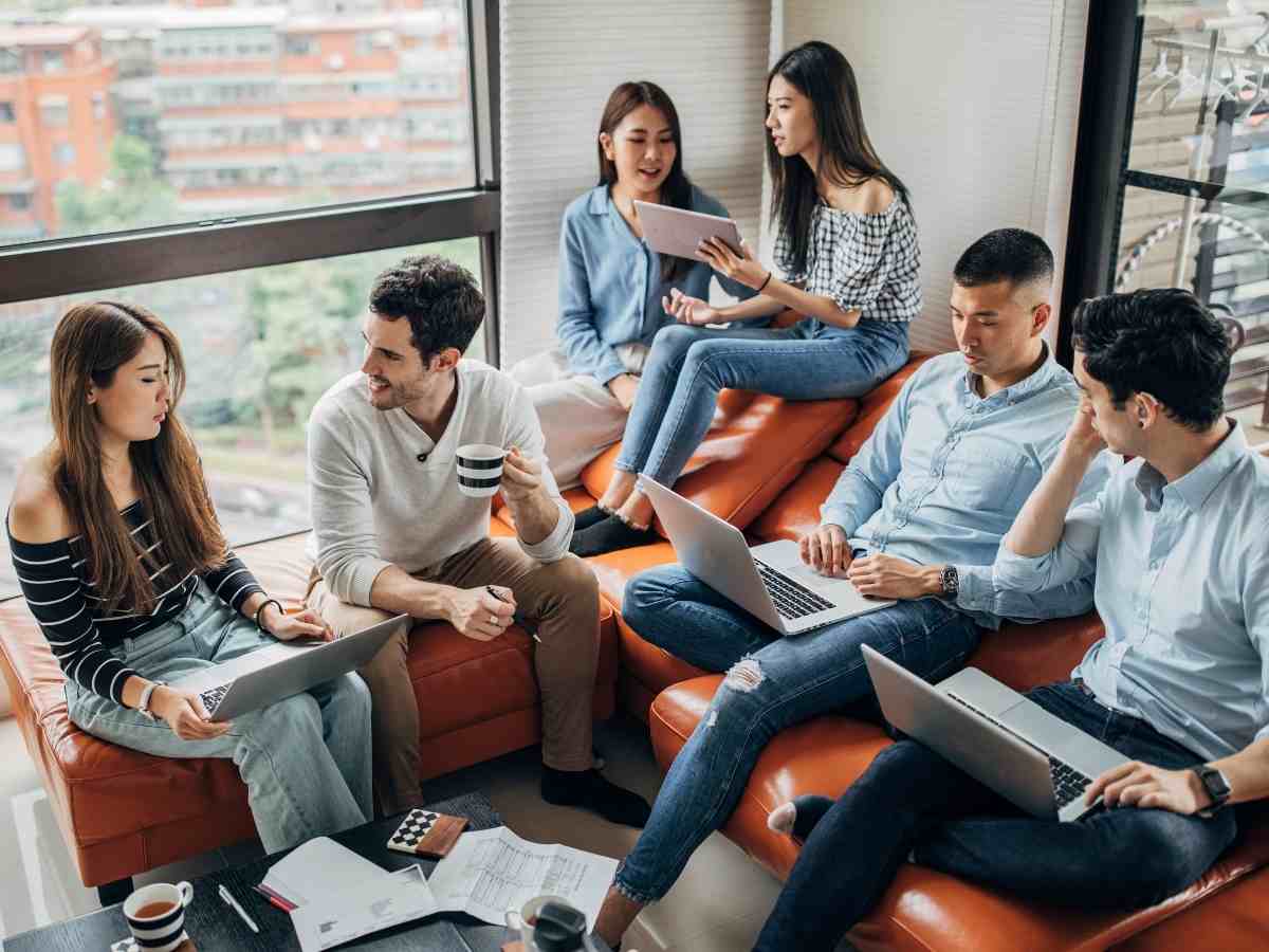 Group of millennials sitting around on an orange leather couch in a high-rise downtown building for article Top 10 Urban Areas in Denver for Millennials for newcomers moving to Denver urban areas.