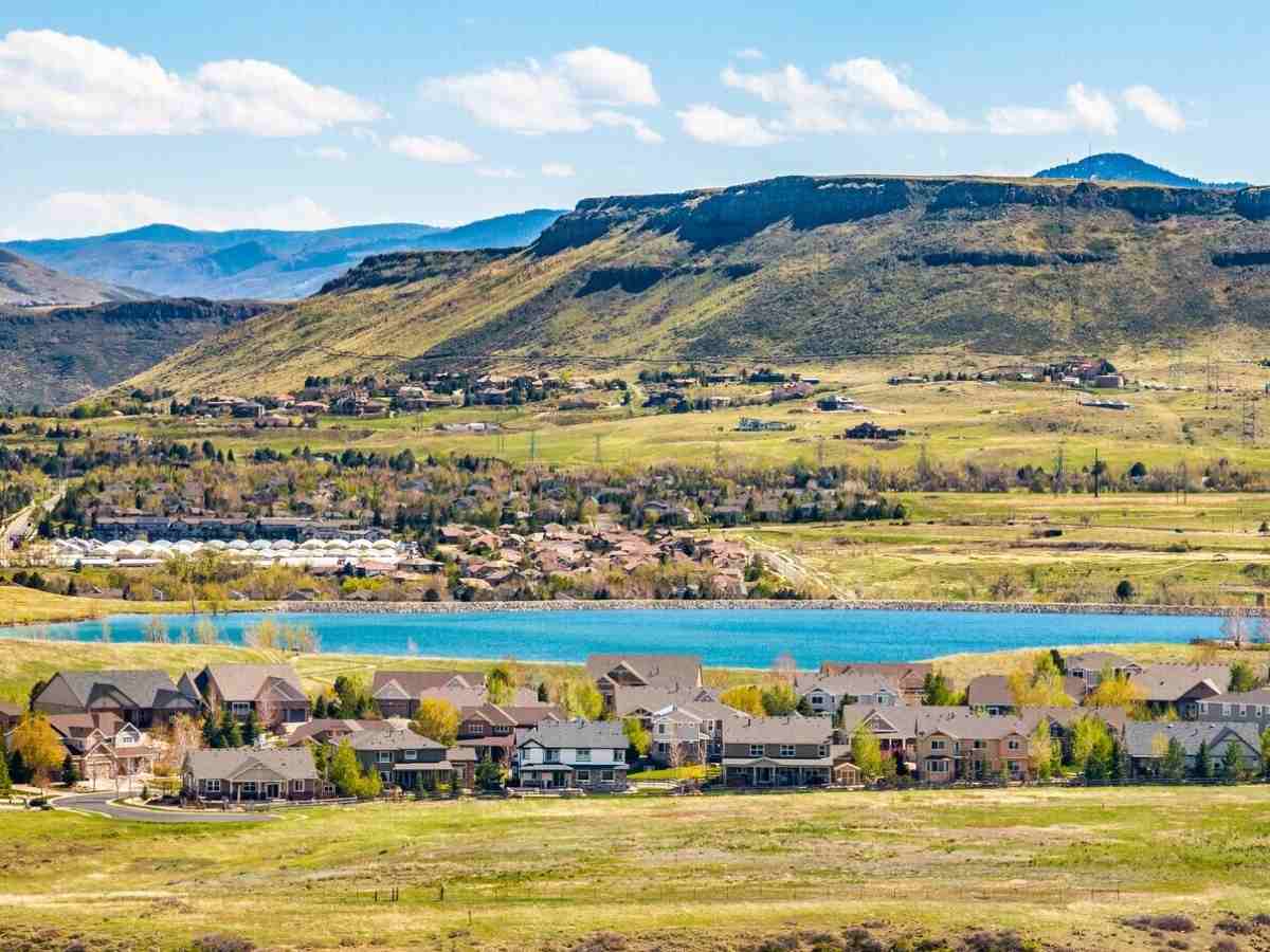 Aerial view of homes and lake with mountains in the background for article West Arvada Named 4th Hottest Neighborhood for newcomers moving to Arvada.