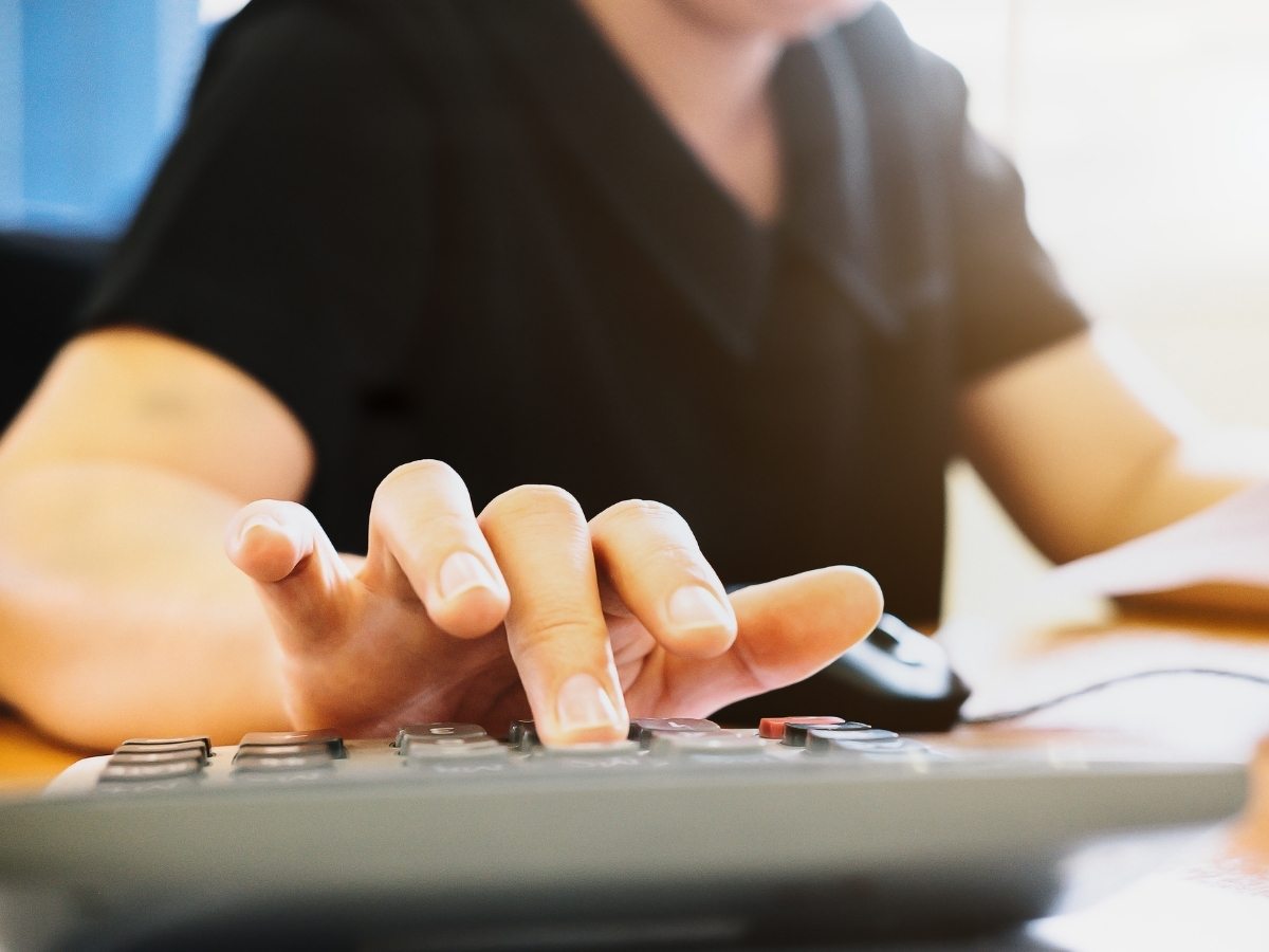 Close up of fingers typing on a calculator for article Cost of Living in Denver in 2025 for newcomers moving to Denver area.