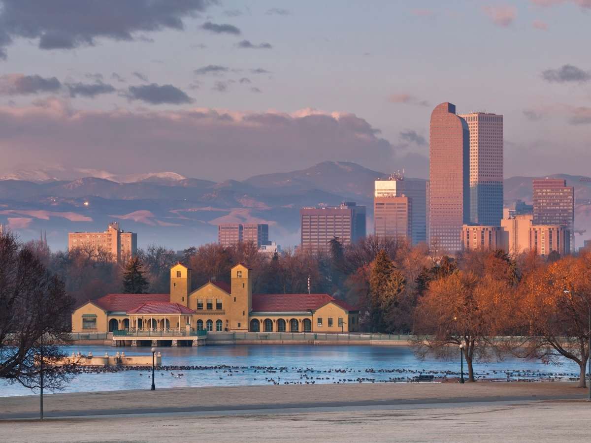 Downtown Denver with park and lake in the foreground and mountains faintly visible in behind the skyline for article Denver Ranked 8th for Most Newcomers moving to Denver area.