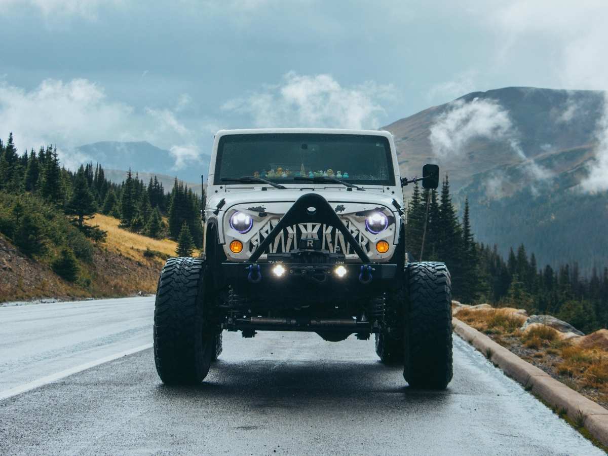 Jeep on road in Colorado with mountains behind it for article Auto Insurance in Colorado for newcomers moving to Denver area.