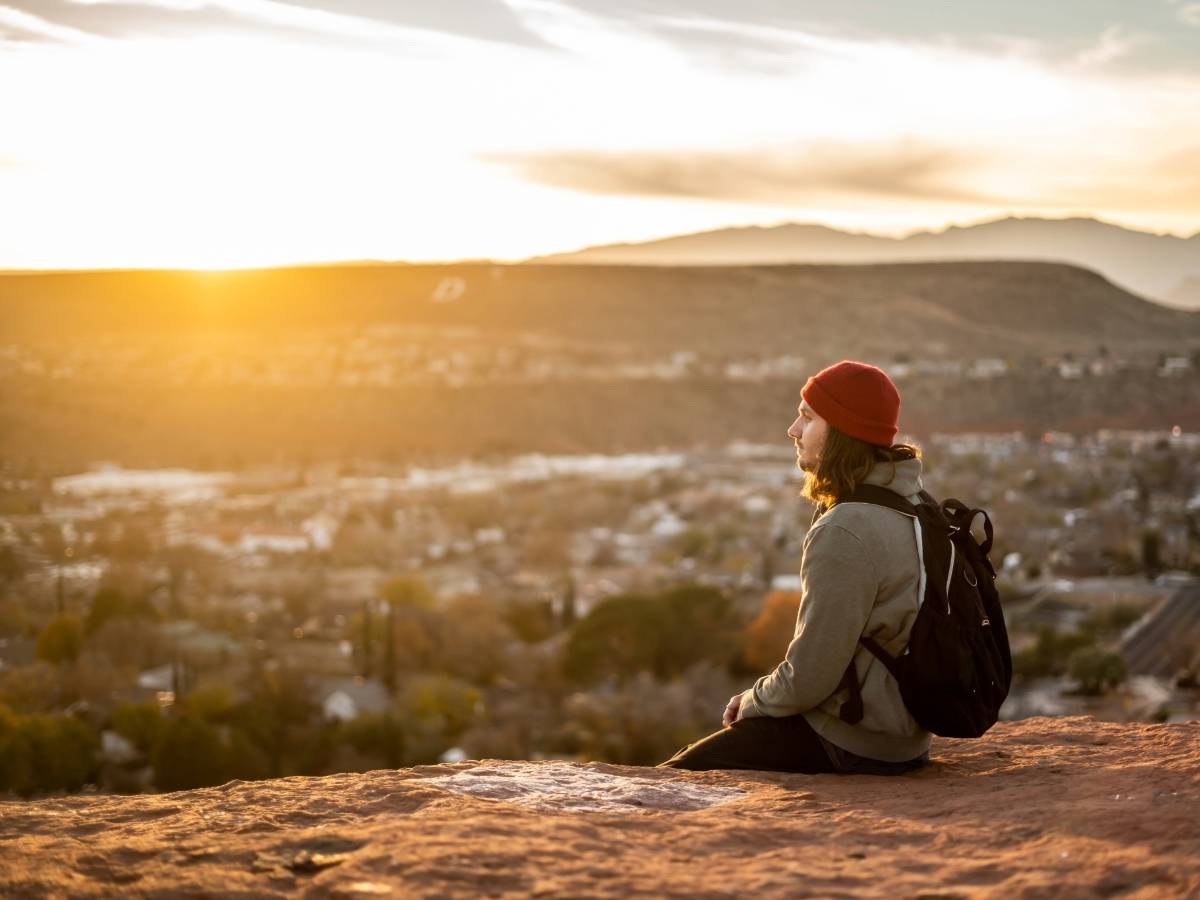 Man sitting on top of mountains looking out over valleys and sunset for article The Mental Health Benefits of Exercise in Denver for newcomers moving to Denver area.