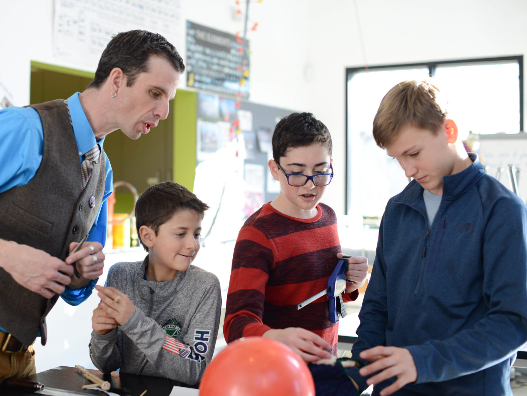 Teacher speaking with three students in a classroom.