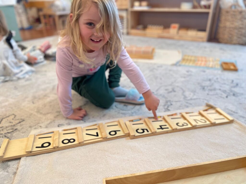 Little girl pointing to #14 on a counting toy at school.