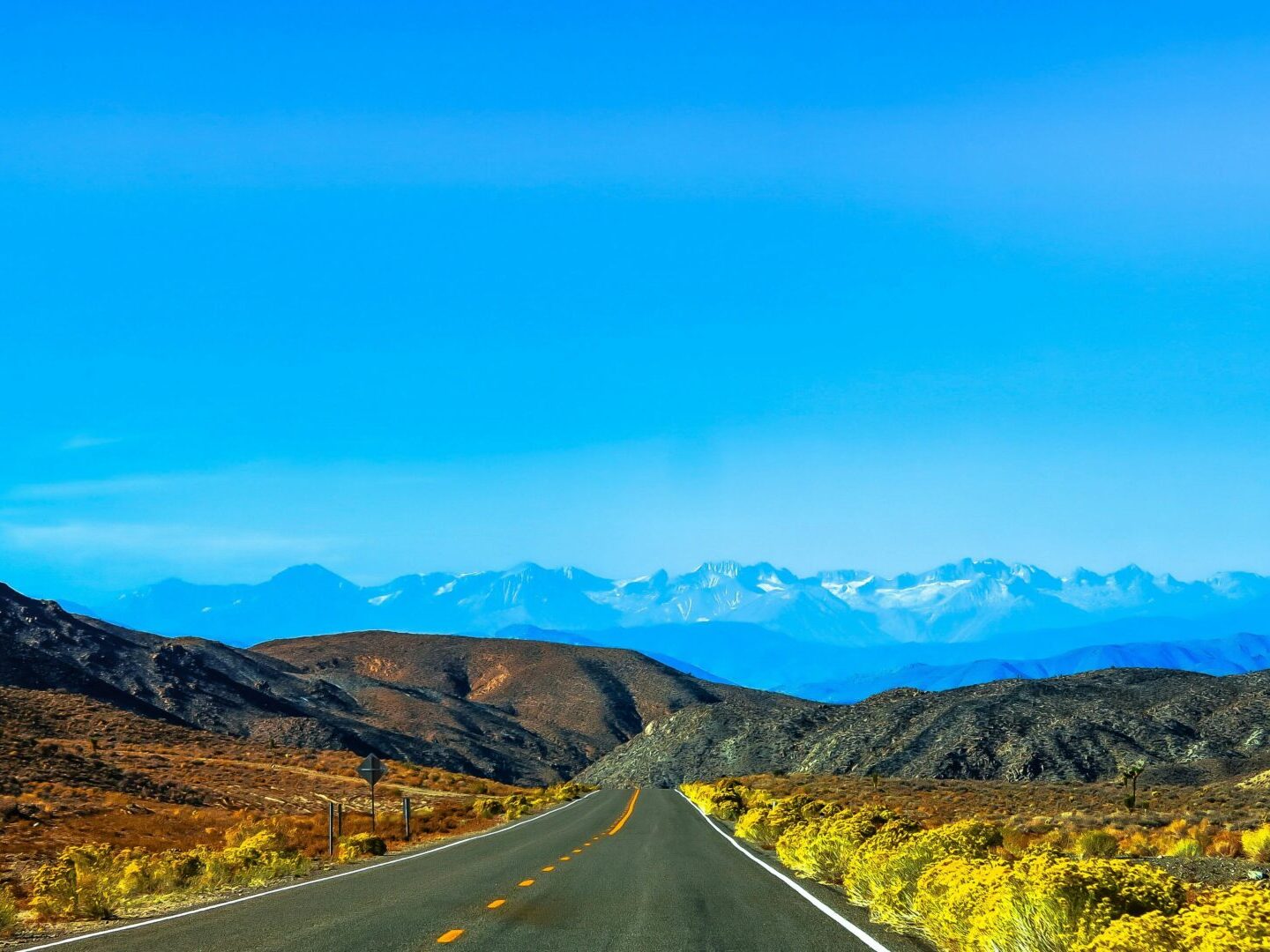 view from highway towards mountains with blue sky