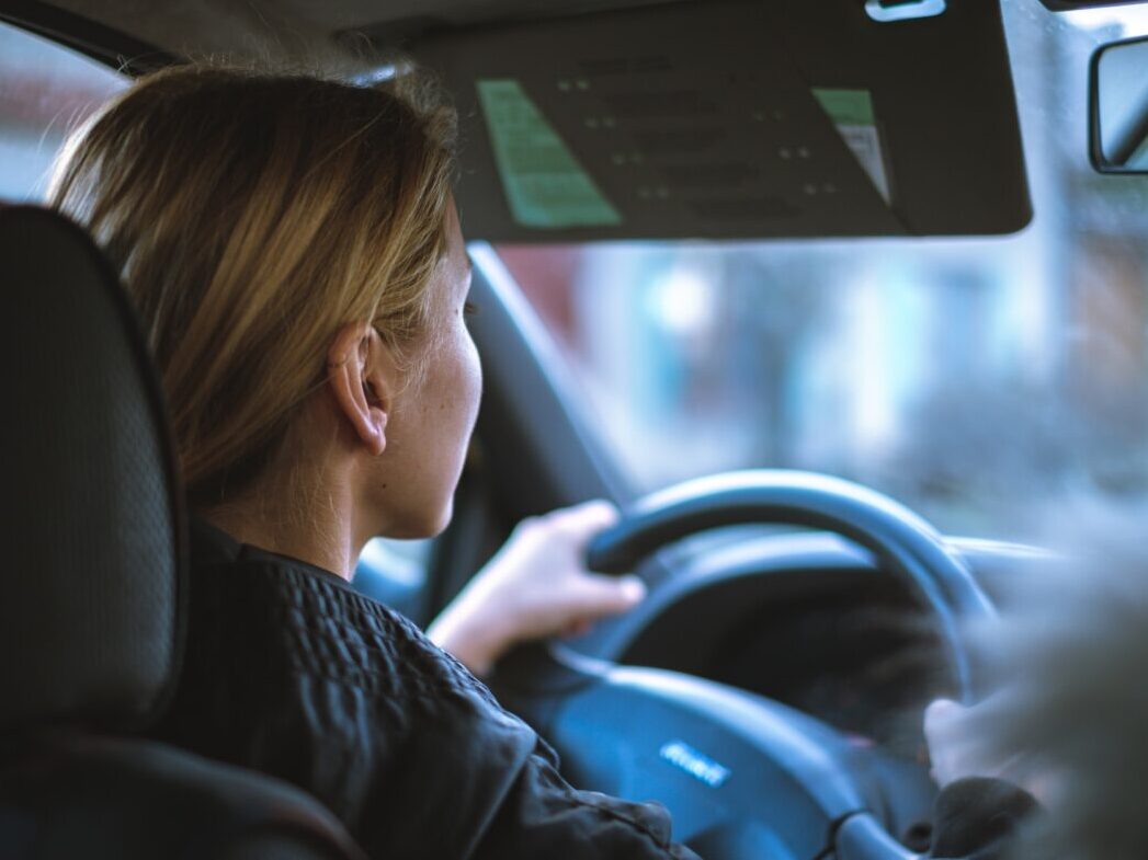 a woman holding the steering wheel in a car while driving