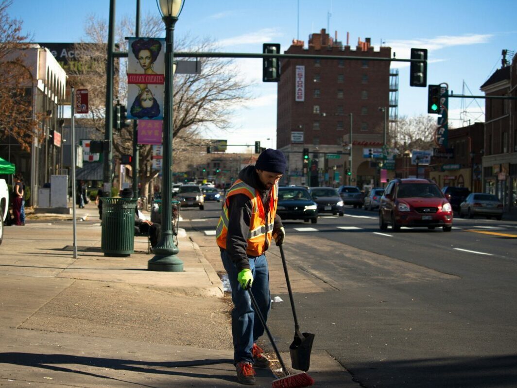 man cleaning the road near a traffic light