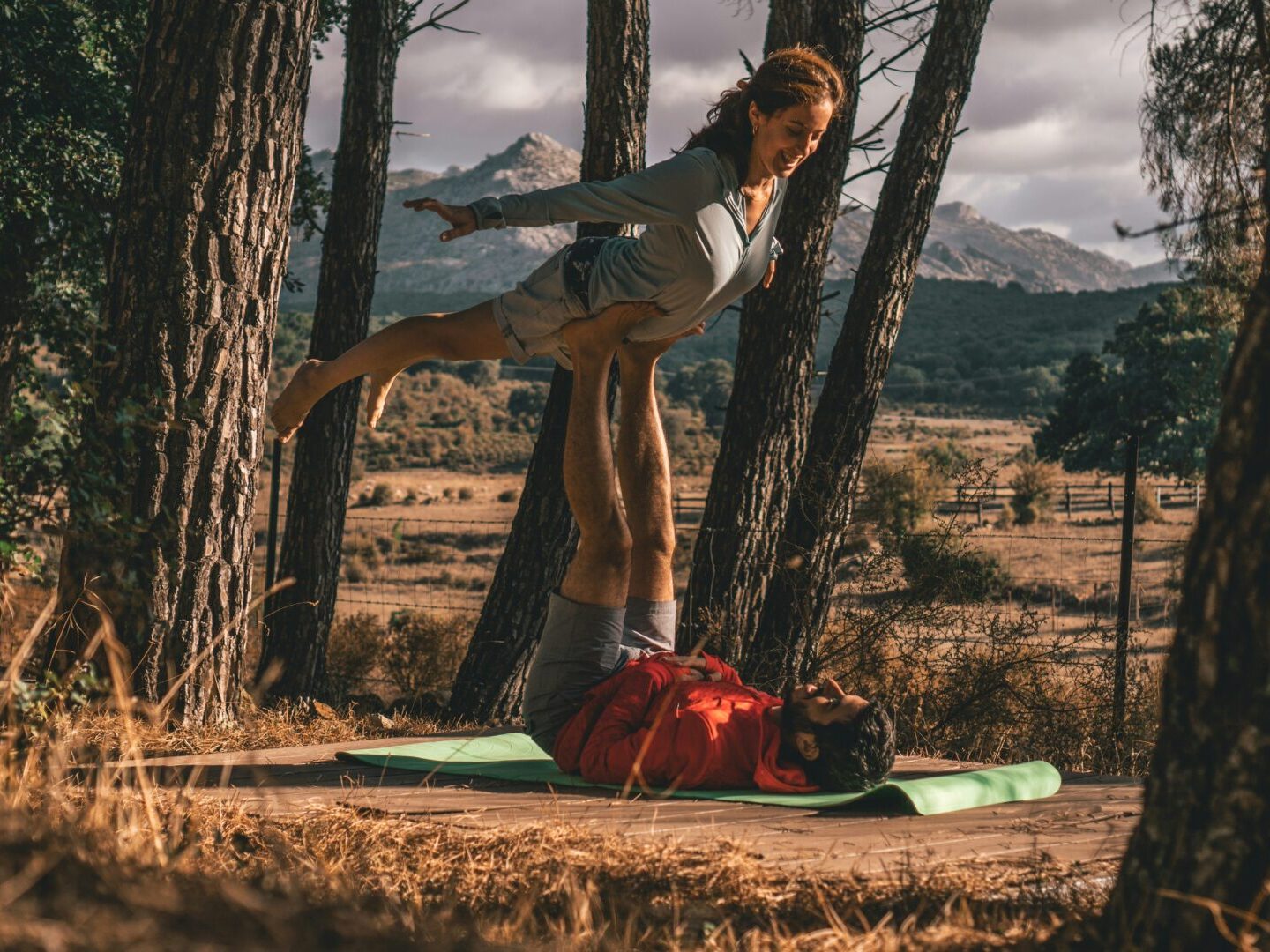 a couple playing some AcroYoga tricks in the wild