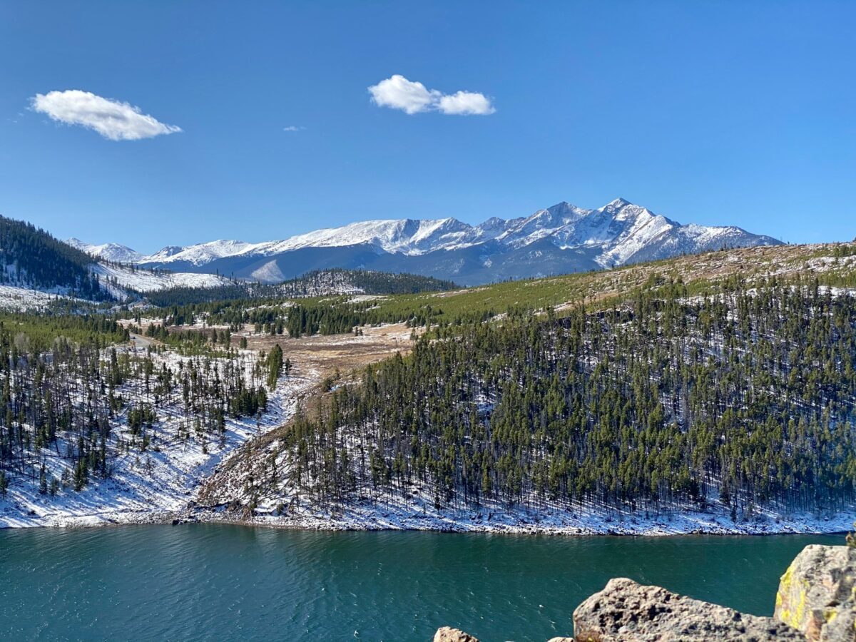 tall green trees on a mountain range in front of Dillon Reservoir