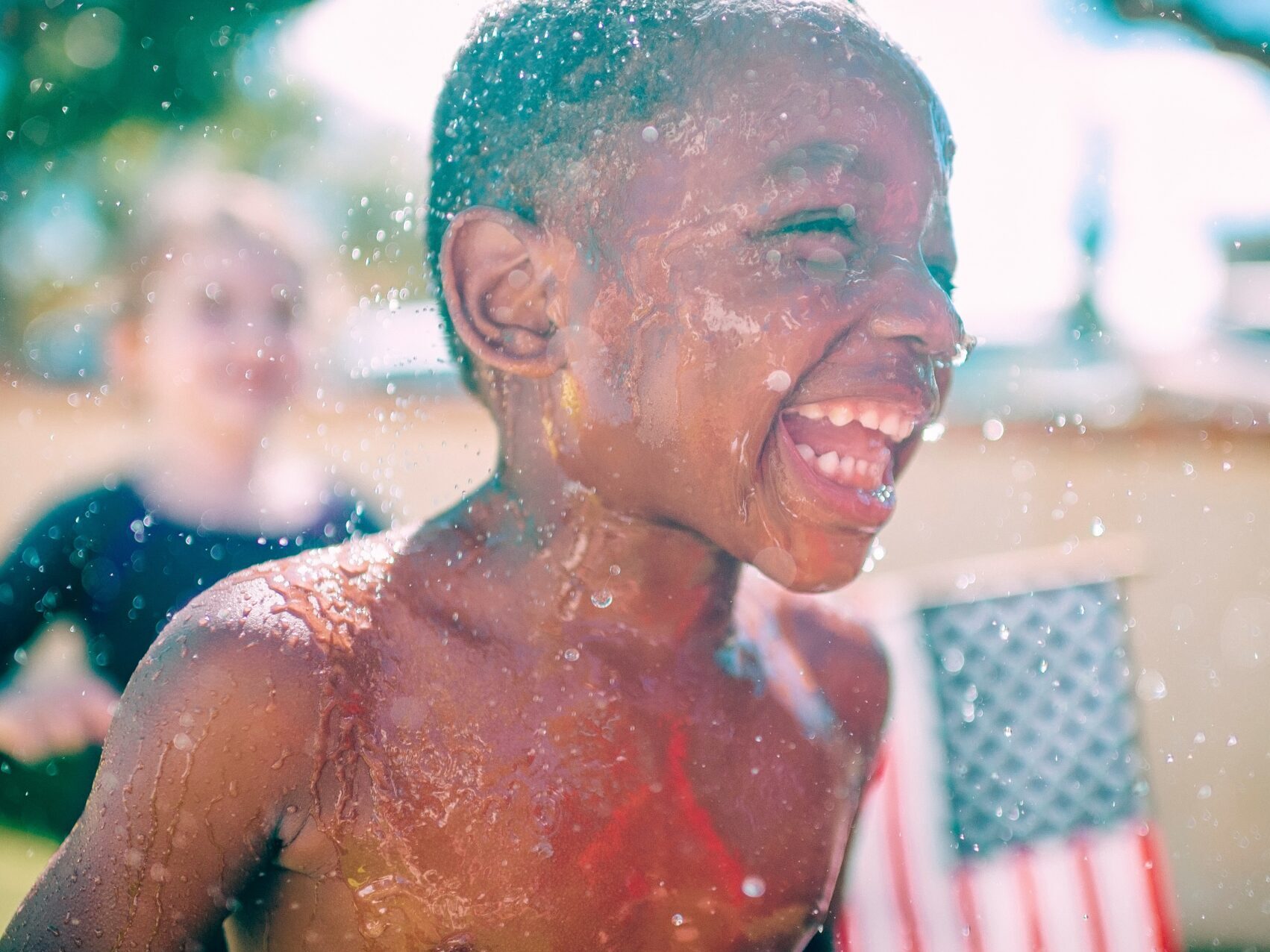 boy smiling playing in sprinkler