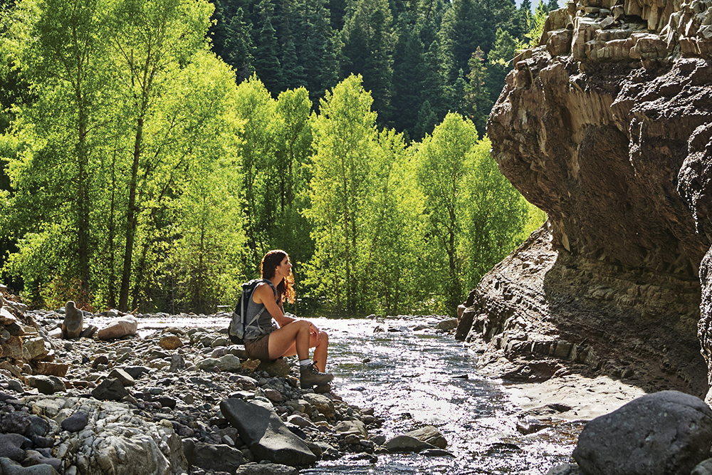 Woman sitting near creek on trail