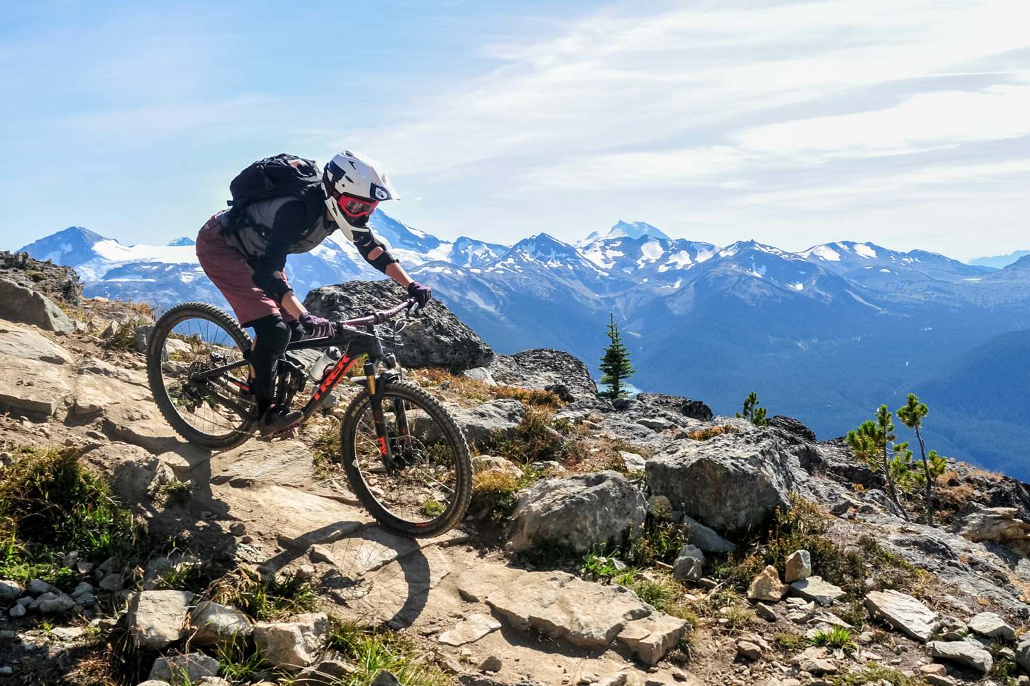 Man riding bike down hill with Mountains in the background