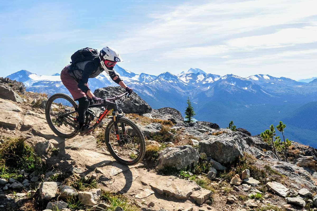 Man riding bike down hill with Mountains in the background