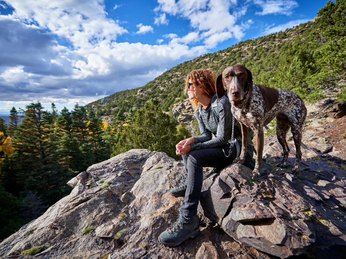 Woman and her dog sitting on rocky area in Colorado outside of Denver.