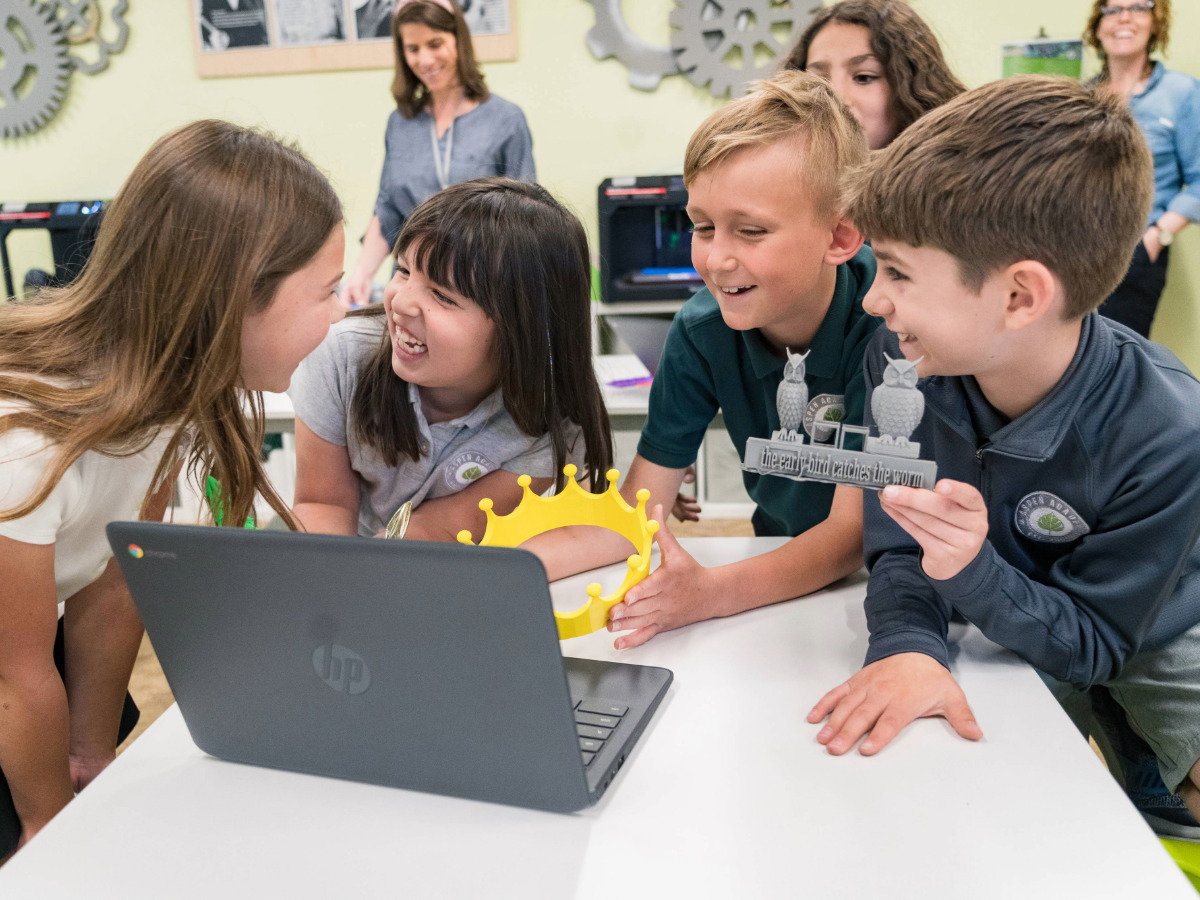 Aspen Academy Kids around a desk with laptop.