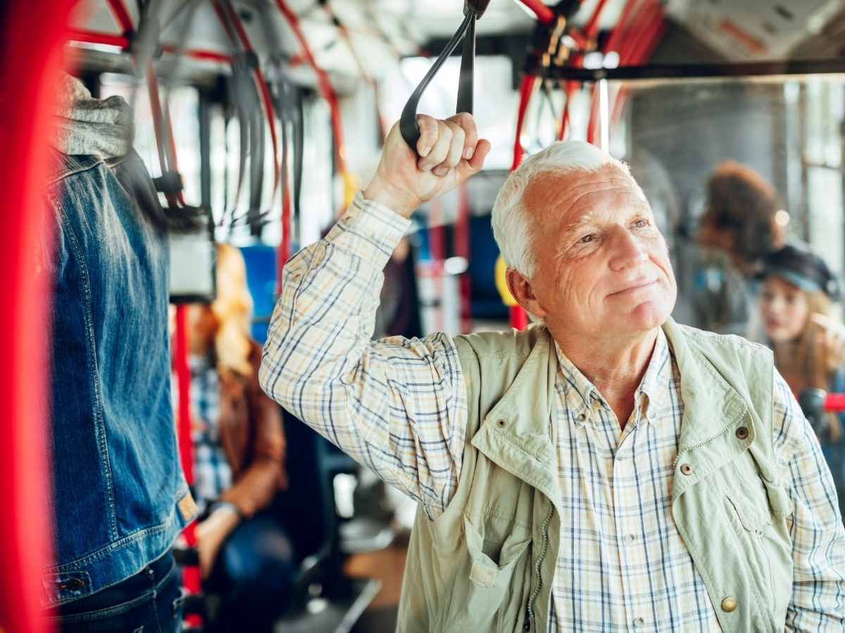 Senior man holding onto strap on bus ride for article Getting Around Denver: Senior Transportation Options for newcomers retiring in Denver.