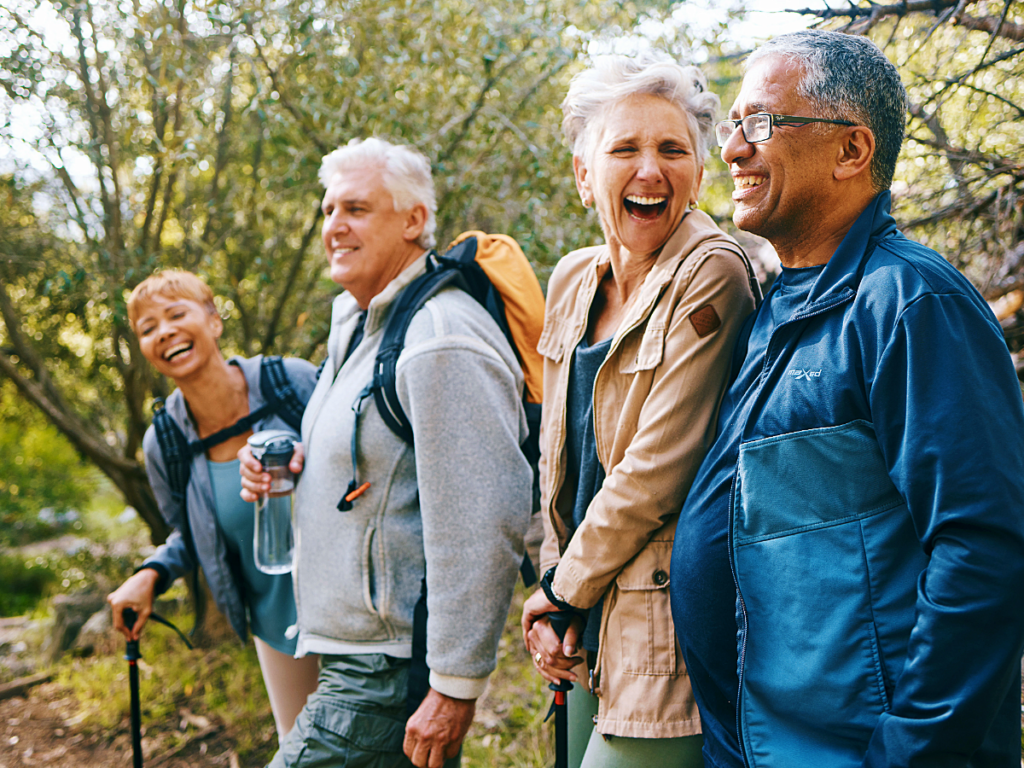 Four diverse seniors out hiking together and laughing.