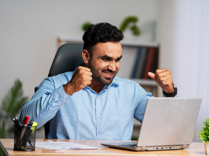 Person celebrating in front of computer after finding contract work online.