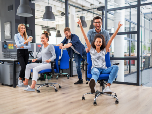 Office chair races with guys pushing girls in chairs on wheels.