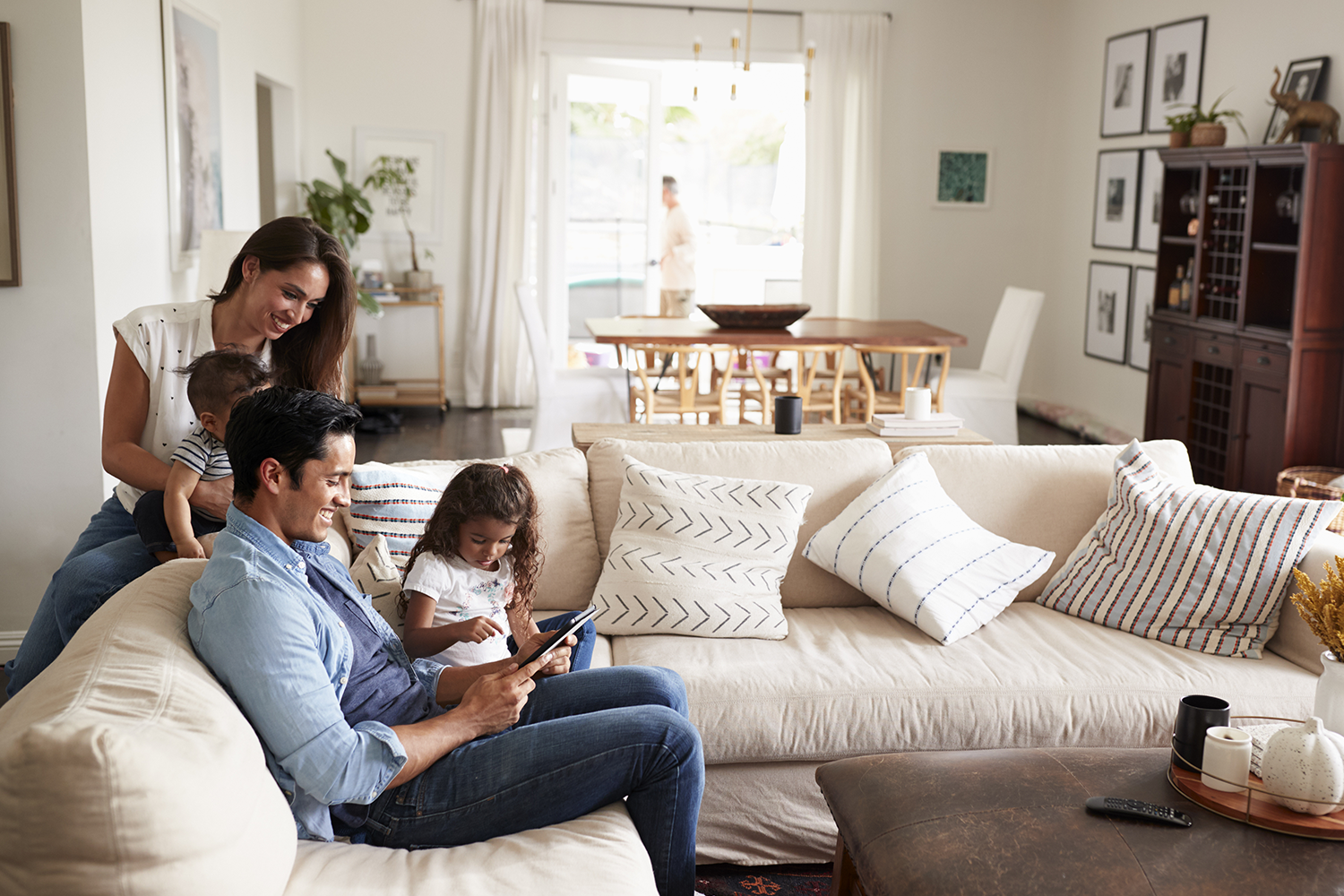 Department Image: LIVE. Family sitting on couch, looking at laptop in living room