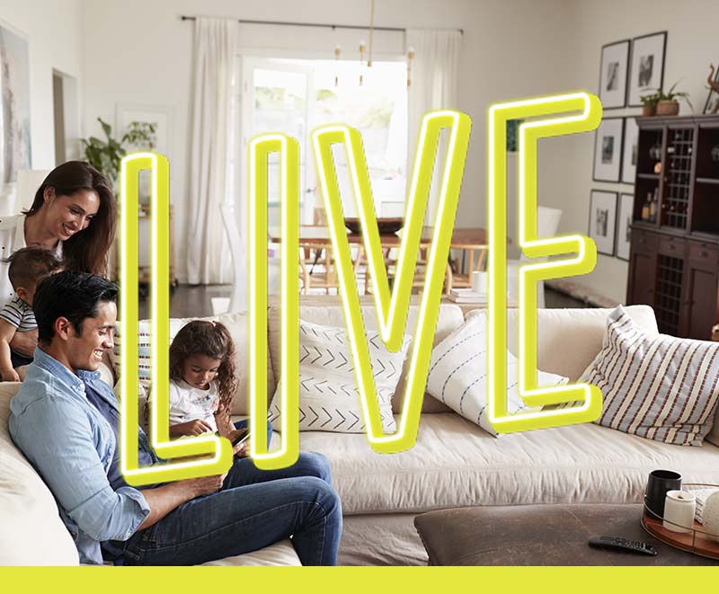 Department Image: LIVE. Family sitting on couch, looking at laptop in living room