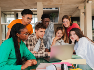 Group of high school students gathered around a computer in school for article - 10 Best College Prep High Schools in Denver.