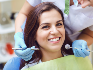 Woman sitting in dental chair smiling for article discover 6 trusted dentists in Denver.