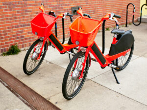 2 red bikes with baskets parked on sidewalk in RiNo district for article Discovering the Most Unique Neighborhood in Denver for newcomers moving to Denver.