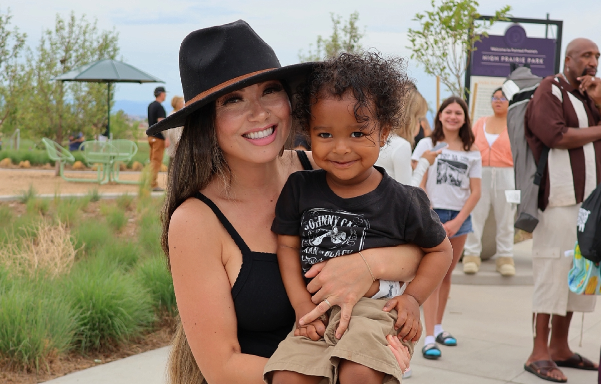 Woman holding child at an outdoor event at Painted Prairie for article Painted Prairie has a home just for you for newcomers moving to Denver.