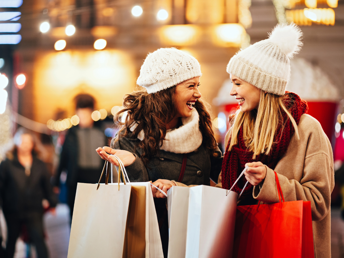 2 Women shopping in winter hats - holding several shopping bags for article Popular Denver Shopping: Malls, Outlets, Street Shopping, and Destination Stores for Newcomers moving to Denver.