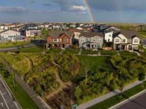 Aerial view of Painted Prairie Master Planned Community showing houses and lots of walking paths for residents and a rainbos in the sky above it for newcomers moving to Denver.