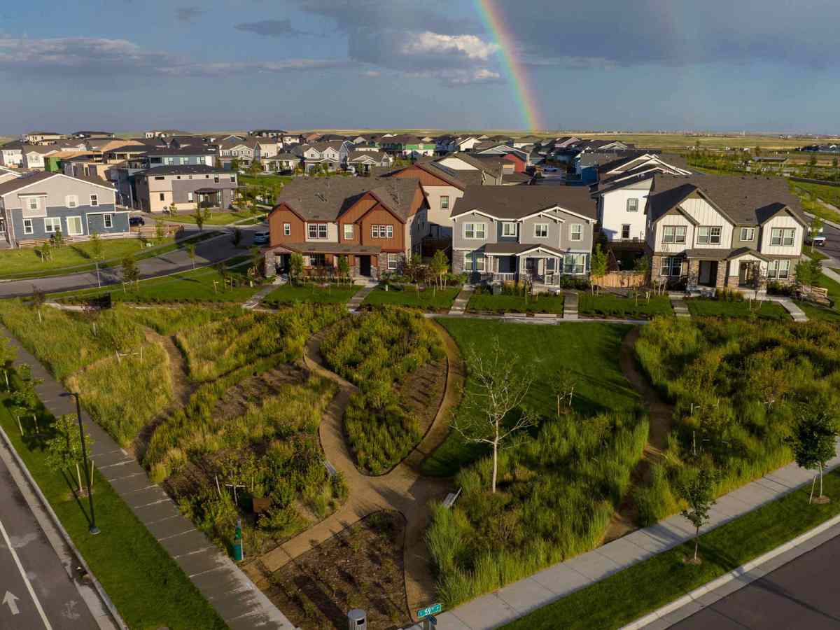 Aerial view of Painted Prairie Master Planned Community showing houses and lots of walking paths for residents and a rainbos in the sky above it for newcomers moving to Denver.