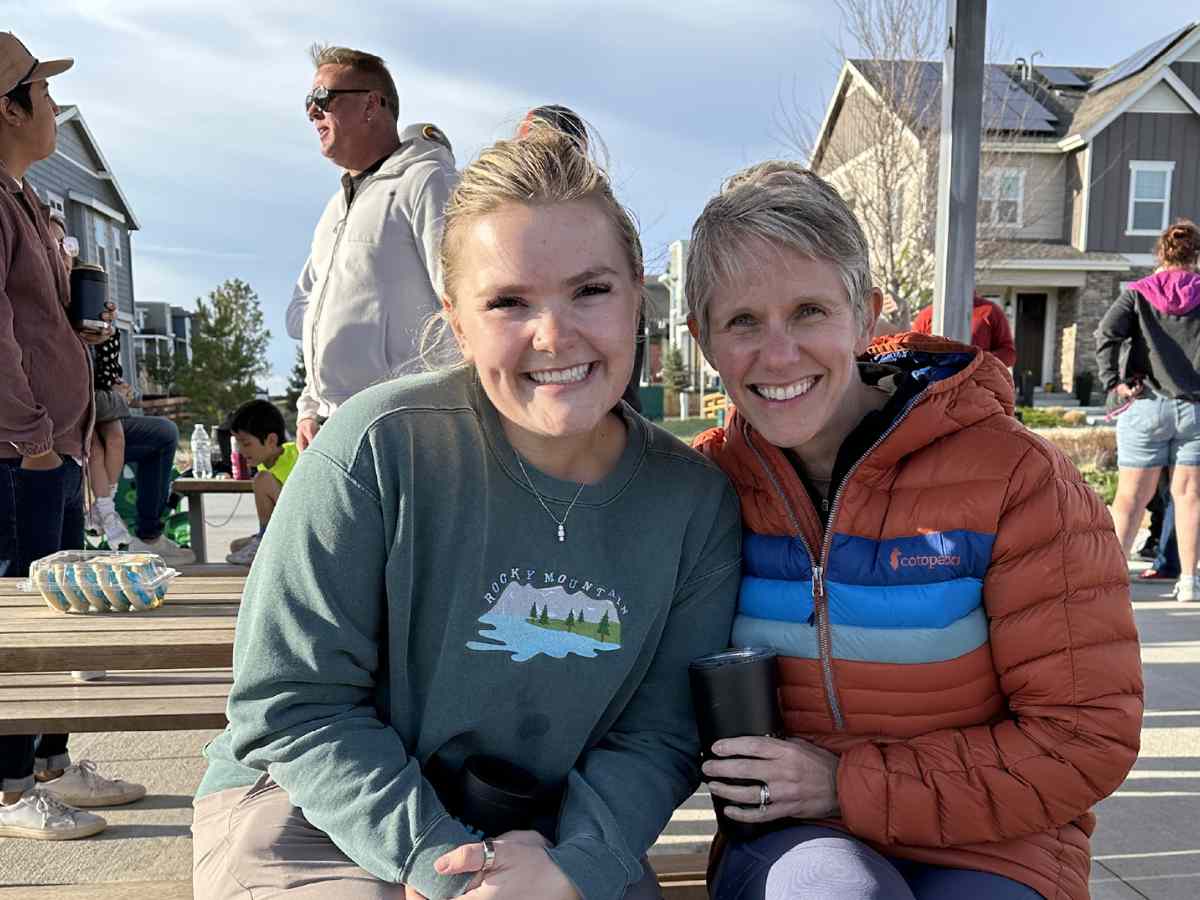 2 female residents sitting outside at an event for article Painted Prairie is Blossoming for newcomers moving to Denver.