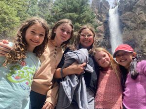 5 girls posing for photo together in front of waterfall for article Montessori Academy of Colorado for newcomers moving to Denver.