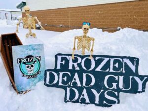 Picture of event sign for Frozen dead guy days with coffin and skeletons with sunglasses for article March Events in Denver for newcomers moving to Denver.