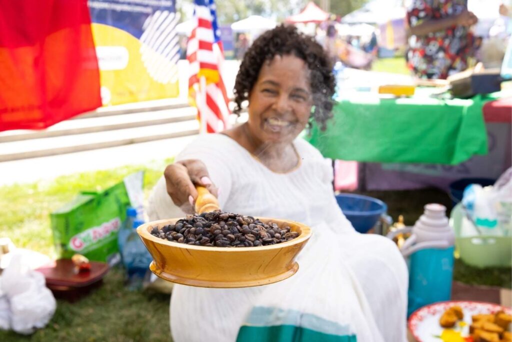 Woman at Global Fest holding out a bowl of beans for article Aurora, Colorado: The World in a City for newcomers moving to Denver or moving within Denver.