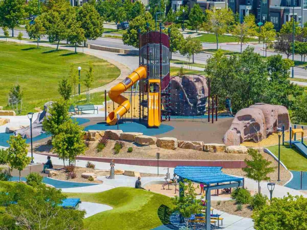 Aerial view of park with playground and lots of green space and walking path in Central Park for article Top Neighborhoods for Families in Denver (2025) for newcomers moving to Denver area.