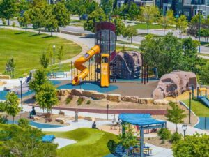 Aerial view of park with playground and lots of green space and walking path in Central Park for article Top Neighborhoods for Families in Denver (2025) for newcomers moving to Denver area.
