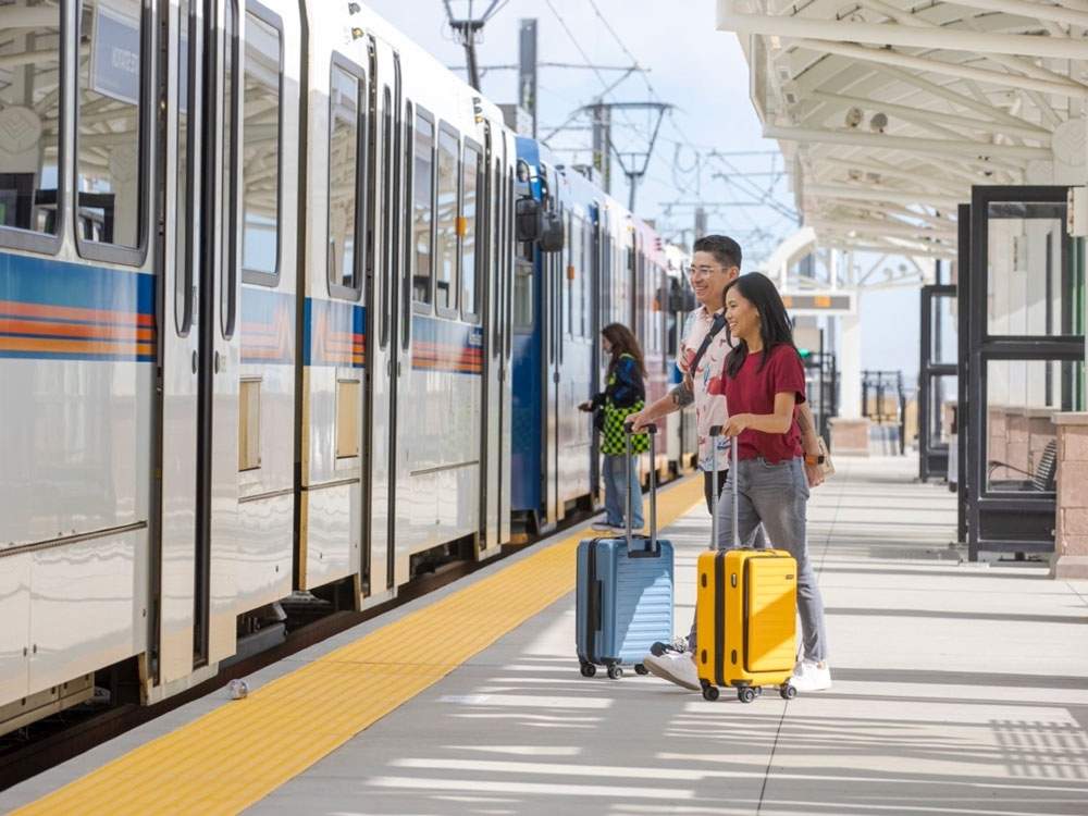 2 People with rolling bags jumping on train for article RidgeGate.