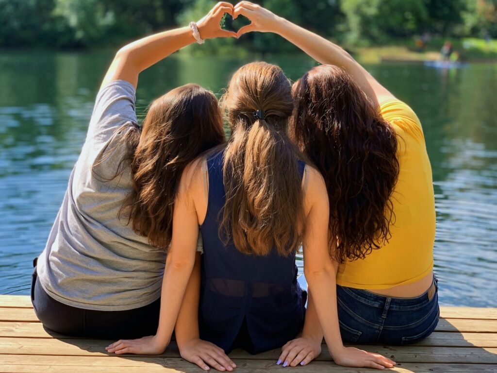 Three girls on a dock by a lake. Best Summer camps in Colorado