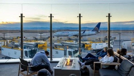 people sitting in front of a glass window looking at a United airplane